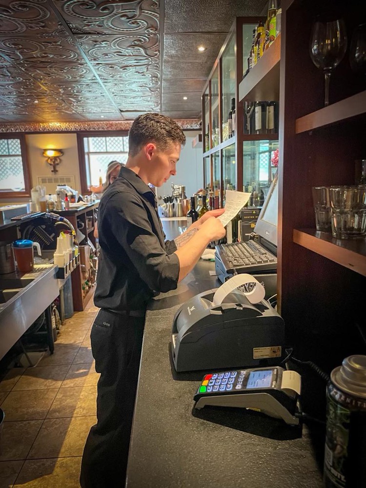 Man behing bar looking at menu